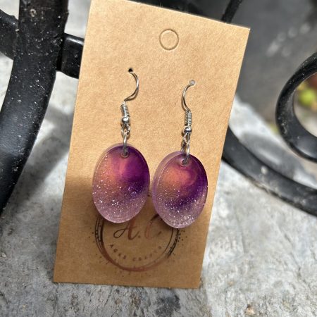 Resin oval earrings with silver glitter and touch if purple
