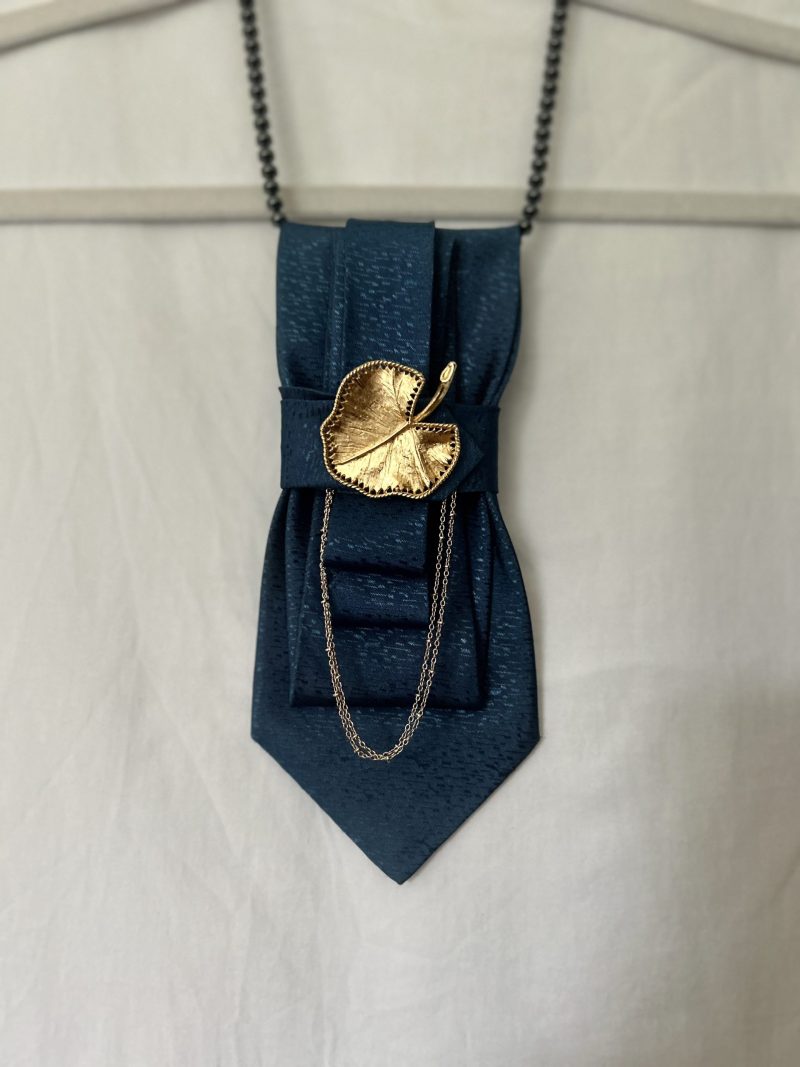 Handmade, elegant, shiny blue necktie accessory adorned by a beautiful golden leaf pendant