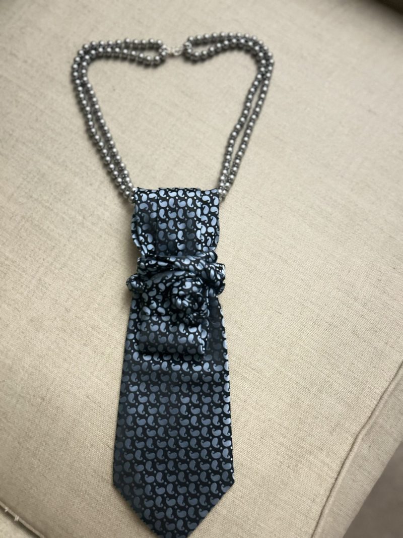 Handmade, necktie accessory in a lovely, funky blue pattern tied with dark silver pearls