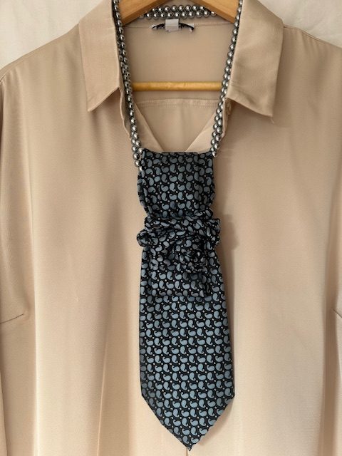 Handmade, necktie accessory in a lovely, funky blue pattern tied with dark silver pearls