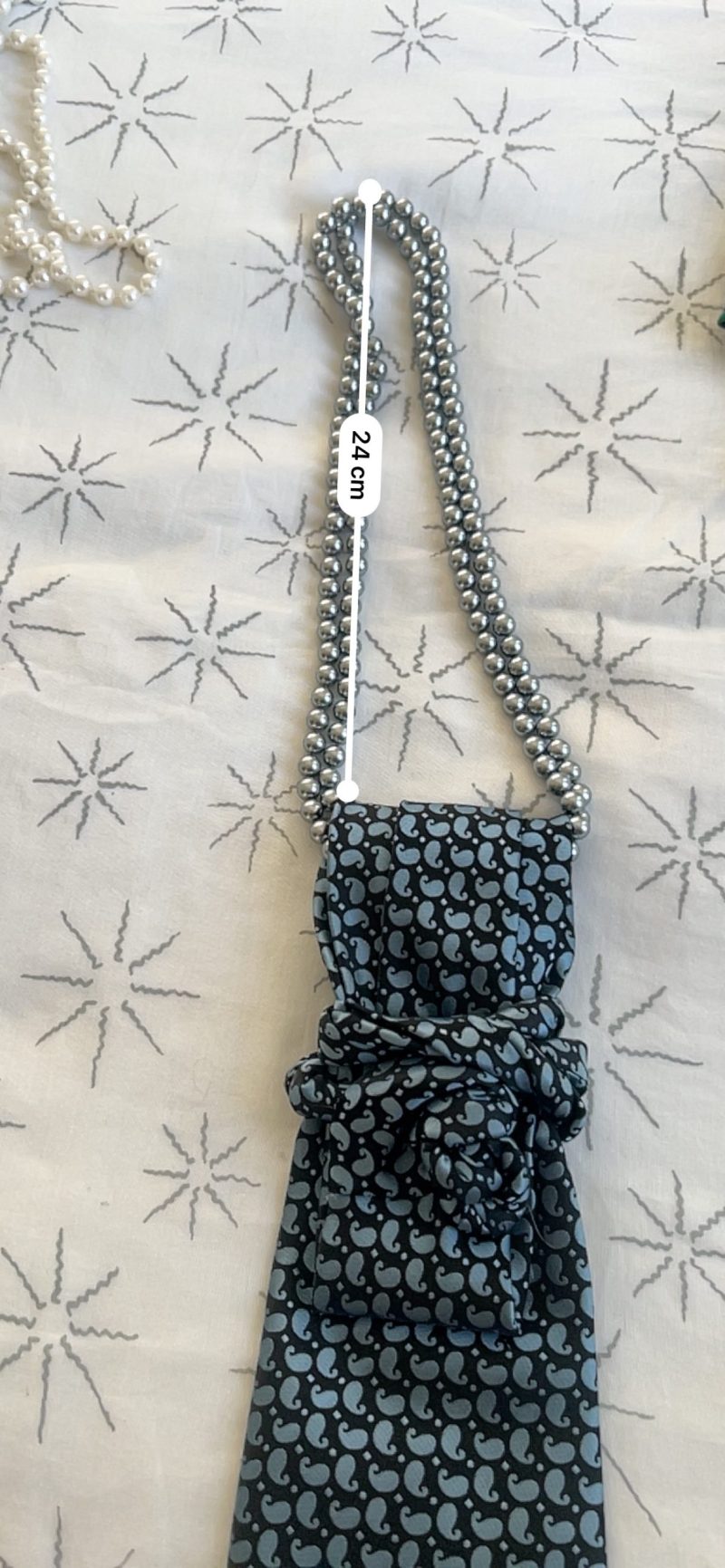 Handmade, necktie accessory in a lovely, funky blue pattern tied with dark silver pearls