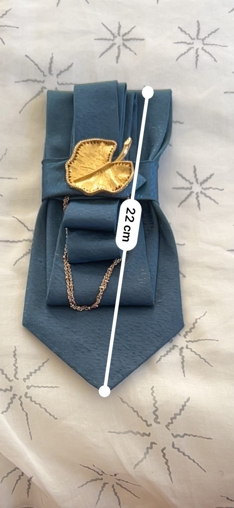 Handmade, elegant, shiny blue necktie accessory adorned by a beautiful golden leaf pendant