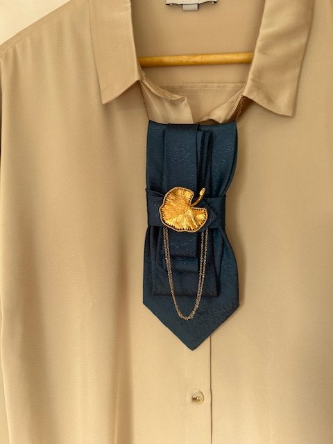 Handmade, elegant, shiny blue necktie accessory adorned by a beautiful golden leaf pendant