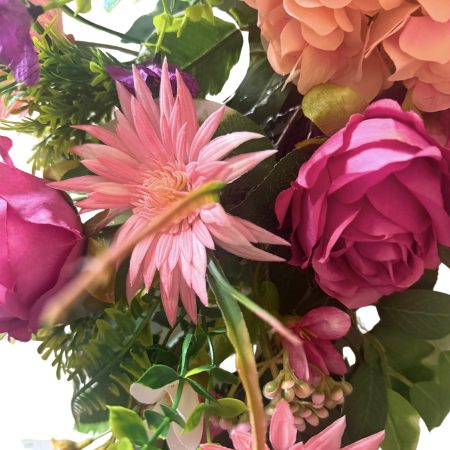 A cheerful wreath with pink and purple flowers on a natural grapevine base H60cm x W50cm