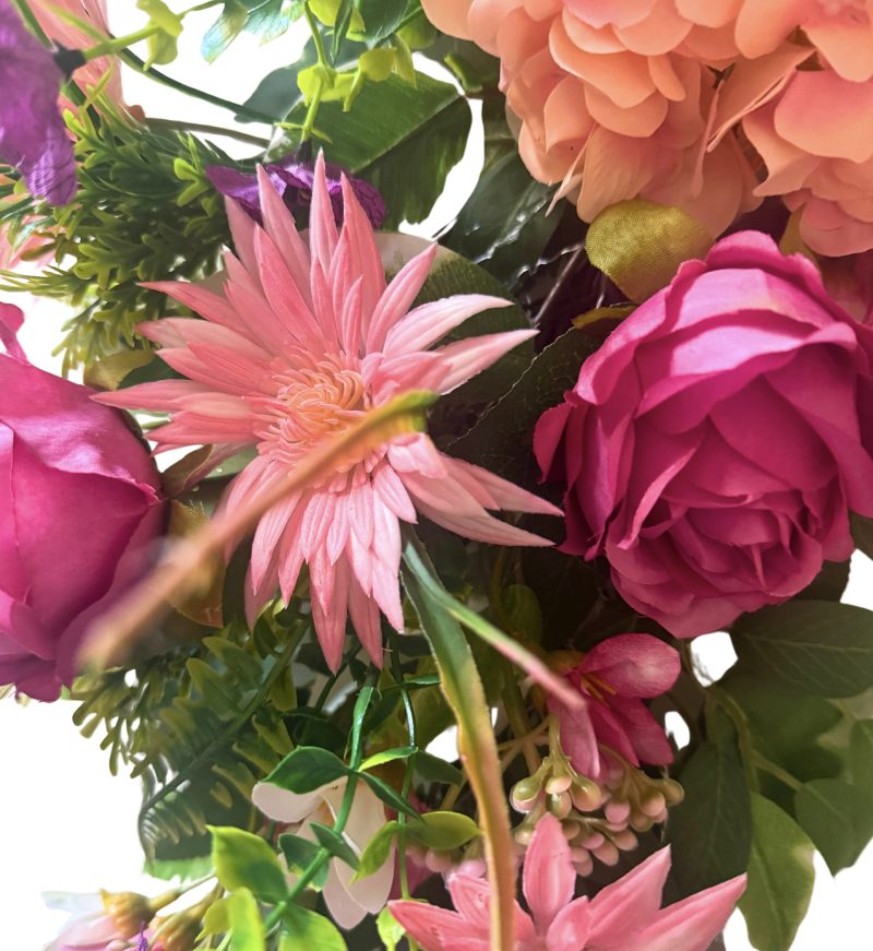 A cheerful wreath with pink and purple flowers on a natural grapevine base H60cm x W50cm