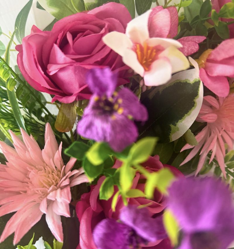 A cheerful wreath with pink and purple flowers on a natural grapevine base H60cm x W50cm