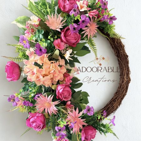 A cheerful wreath with pink and purple flowers on a natural grapevine base H60cm x W50cm