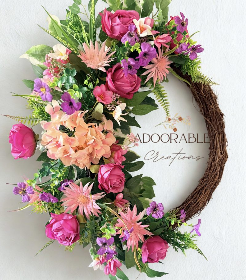 A cheerful wreath with pink and purple flowers on a natural grapevine base H60cm x W50cm