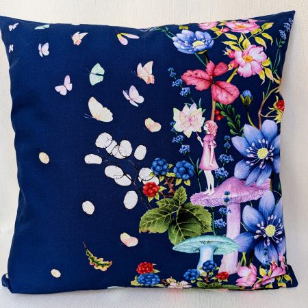 Decorative cushion cover showing a girl standing on a mushroom holding a butterfly surrounded by flowers and floating butterflies on a navy background.