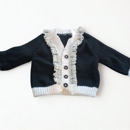 Long sleeved black cardigan with white trim. A lovely lace trim up the front and around the neck can be added. Comes is various sizes. Acrylic yarn for easy care.