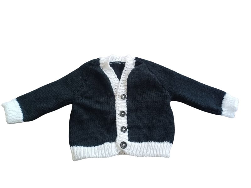 Long sleeved black cardigan with white trim. A lovely lace trim up the front and around the neck can be added. Comes is various sizes. Acrylic yarn for easy care.