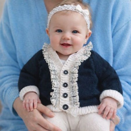 Long sleeved black cardigan with white trim. A lovely lace trim up the front and around the neck can be added. Comes is various sizes. Acrylic yarn for easy care.