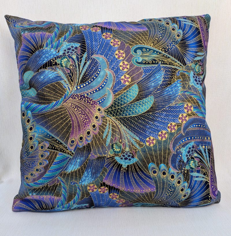 Front of decorative cushion cover with intricate peacock feather pattern in blue, purple, and gold on black background, 18 inch, zipped and lined