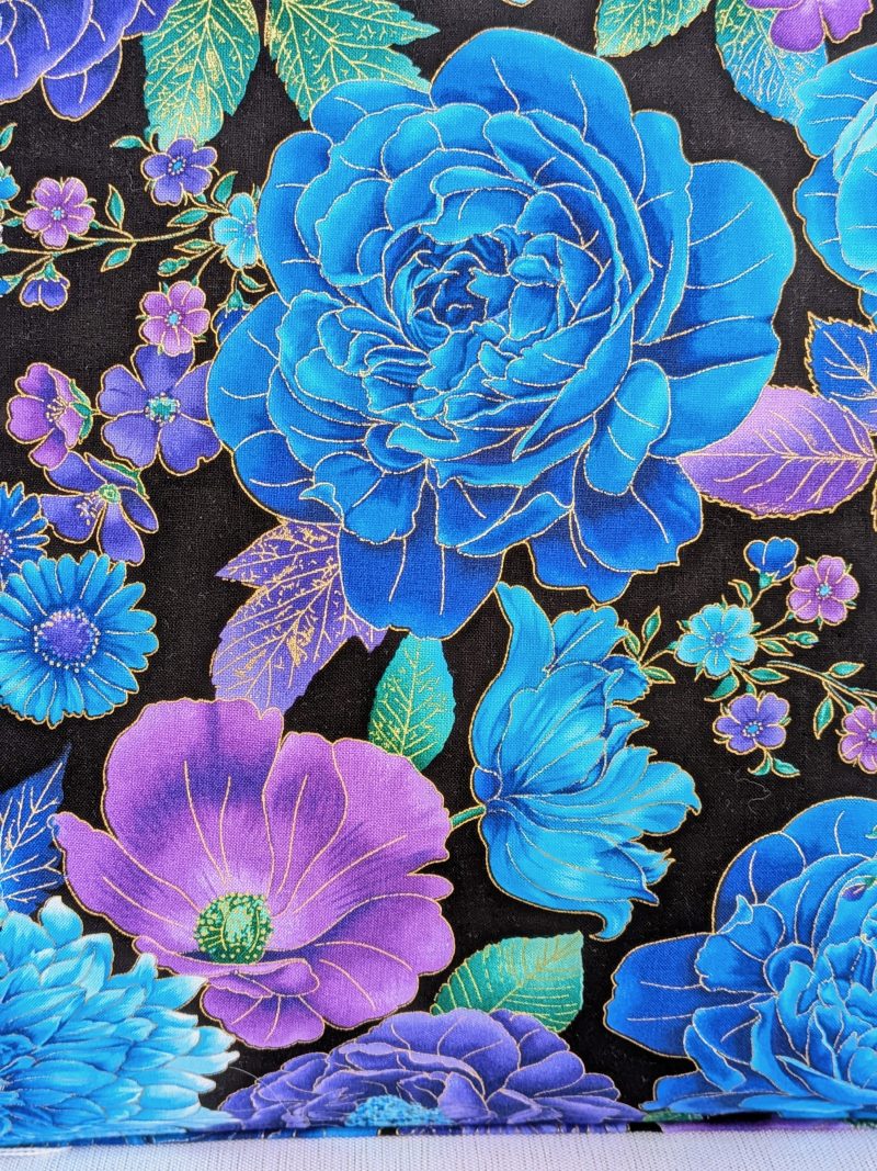 Front detail of decorative throw pillow cover with vibrant blue and purple floral pattern on a black background, featuring detailed blossoms and leaves.