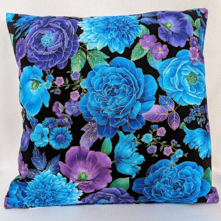Reverse of decorative throw pillow cover with vibrant blue and purple floral pattern on a black background, featuring detailed blossoms and leaves.