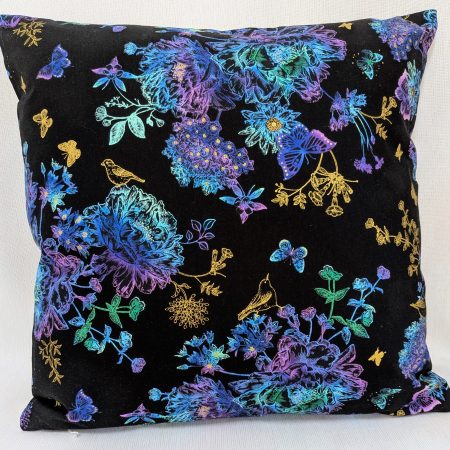 Reverse of black cushion cover featuring colourful rainbow floral pattern with butterflies and gold accents, lined with a zip closure