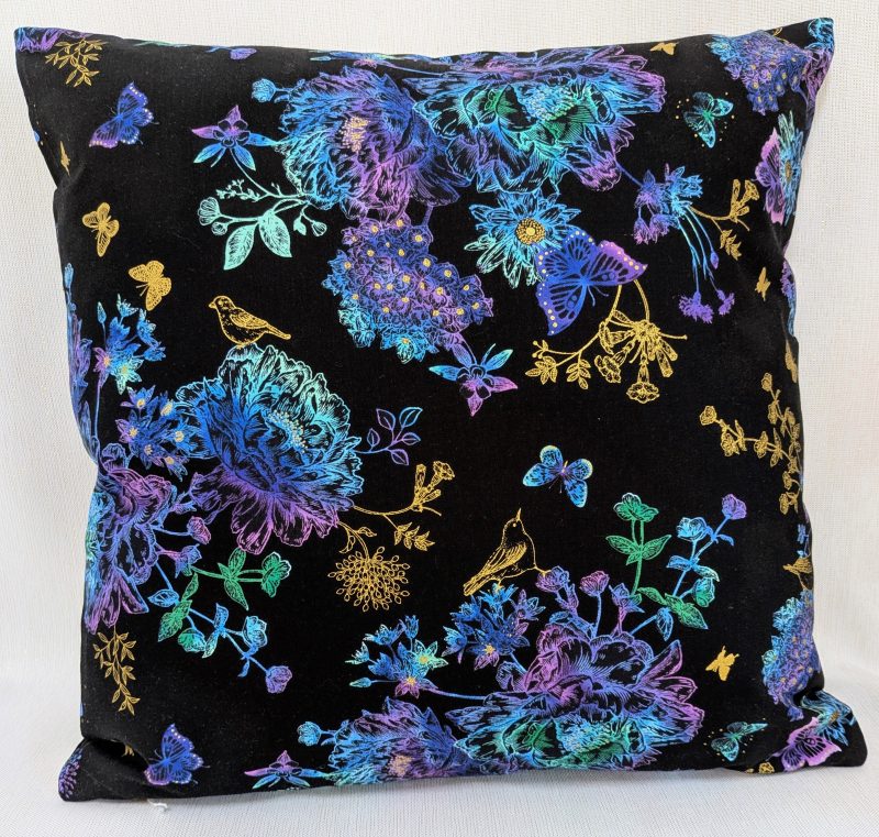 Reverse of black cushion cover featuring colourful rainbow floral pattern with butterflies and gold accents, lined with a zip closure