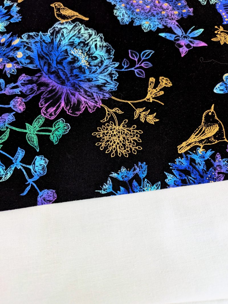 Lining detail of black cushion cover featuring colourful rainbow floral pattern with butterflies and gold accents, lined with a zip closure