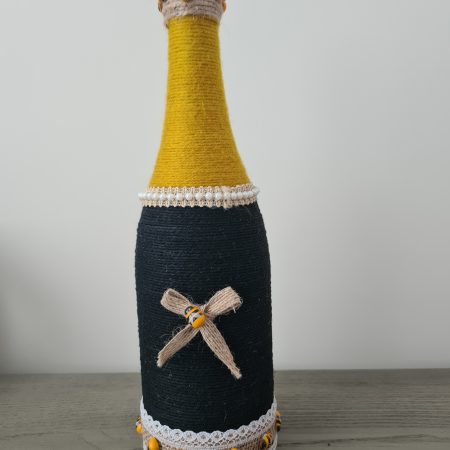 Upcycled wine bottle wrapped with yellow & black yarn with bumble bee decor