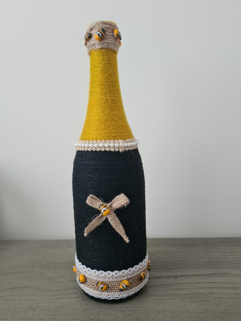 Upcycled wine bottle wrapped with yellow & black yarn with bumble bee decor