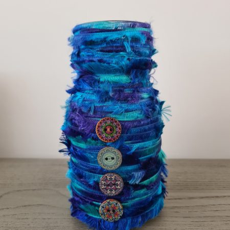 Upcycled glass jar wrapped with blue yarn and decorated with wooden buttons