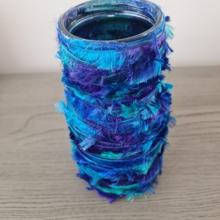 Upcycled glass jar wrapped with blue yarn and decorated with wooden buttons