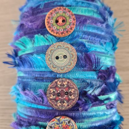 Upcycled glass jar wrapped with blue yarn and decorated with wooden buttons