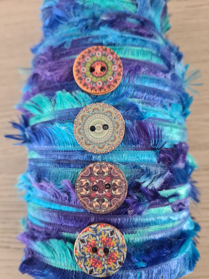 Upcycled glass jar wrapped with blue yarn and decorated with wooden buttons
