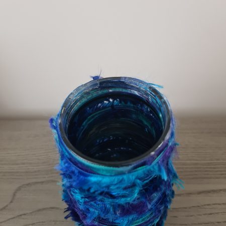 Upcycled glass jar wrapped with blue yarn and decorated with wooden buttons
