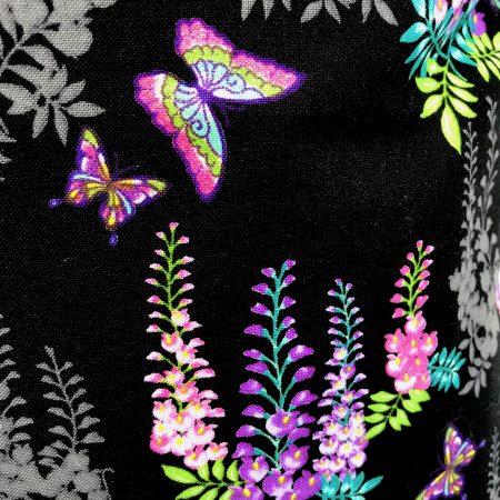Front detail of black cushion cover with bright pink and purple floral pattern and butterflies, 18 inch square, lined with zip fastening