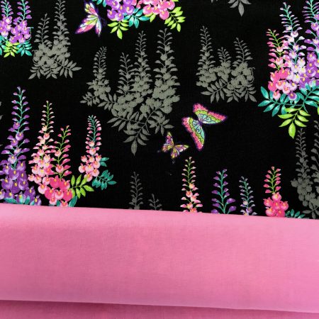 Lining detail of black cushion cover with bright pink and purple floral pattern and butterflies, 18 inch square, lined with zip fastening