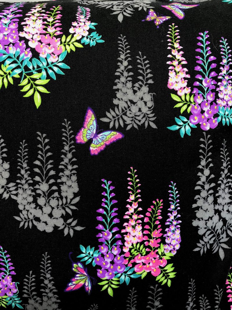 Reverse detail of black cushion cover with bright pink and purple floral pattern and butterflies, 18 inch square, lined with zip fastening