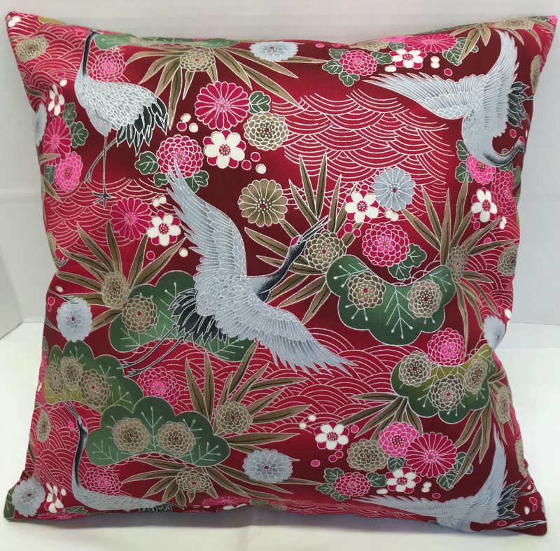 Front of red cushion cover with Japanese crane and floral pattern, featuring flying cranes and detailed blossoms on decorative fabric