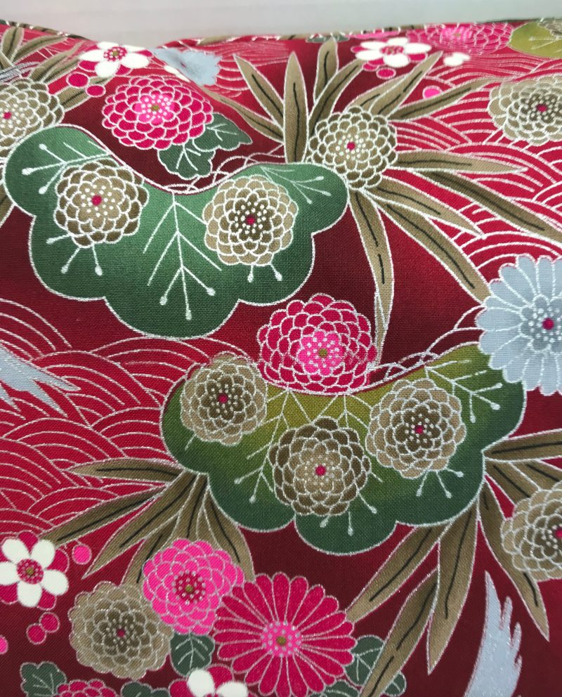 Reverse detail of red cushion cover with Japanese crane and floral pattern, featuring flying cranes and detailed blossoms on decorative fabric