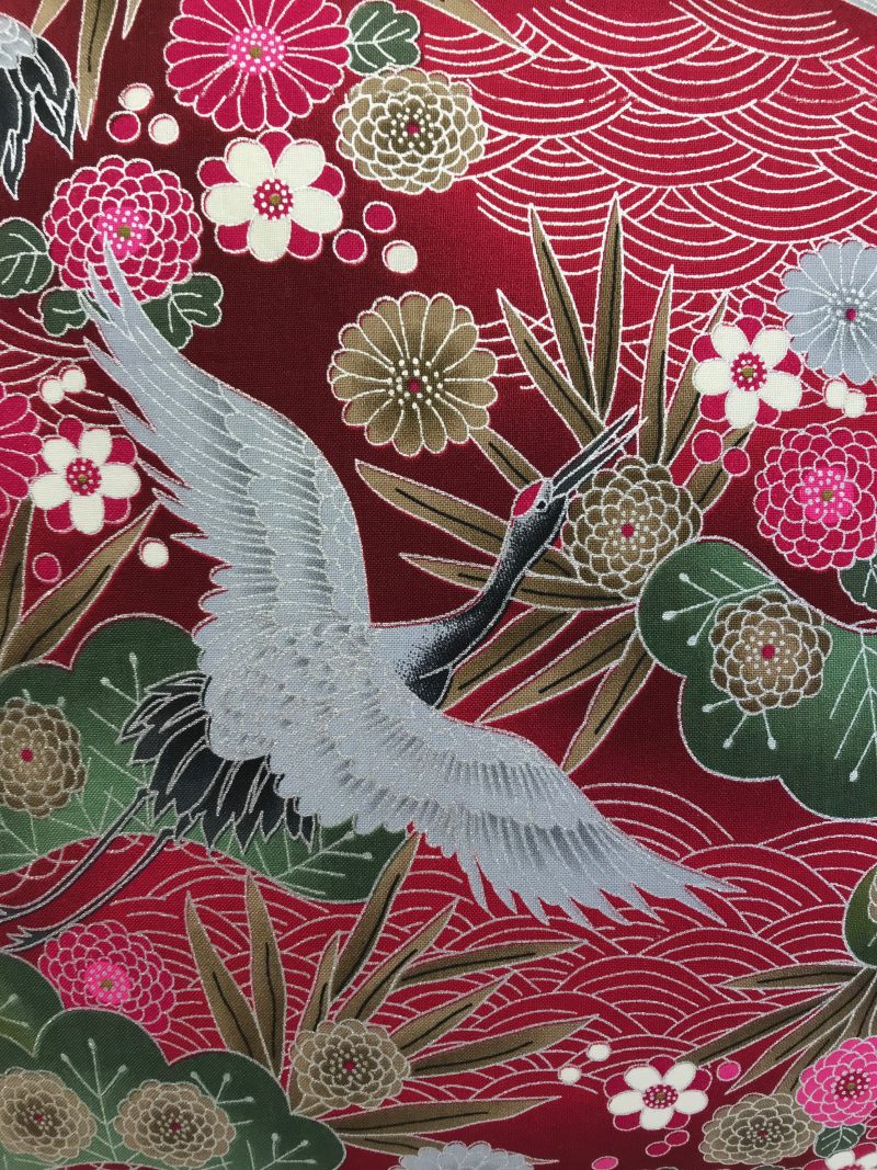 Front detail red cushion cover with Japanese crane and floral pattern, featuring flying cranes and detailed blossoms on decorative fabric