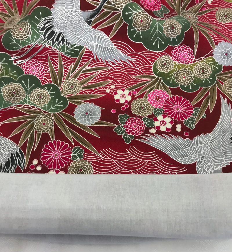 Lining detail of red cushion cover with Japanese crane and floral pattern, featuring flying cranes and detailed blossoms on decorative fabric