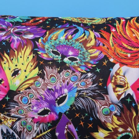 Detail of colourful cushion cover with vibrant carnival masks and feather design on a black background