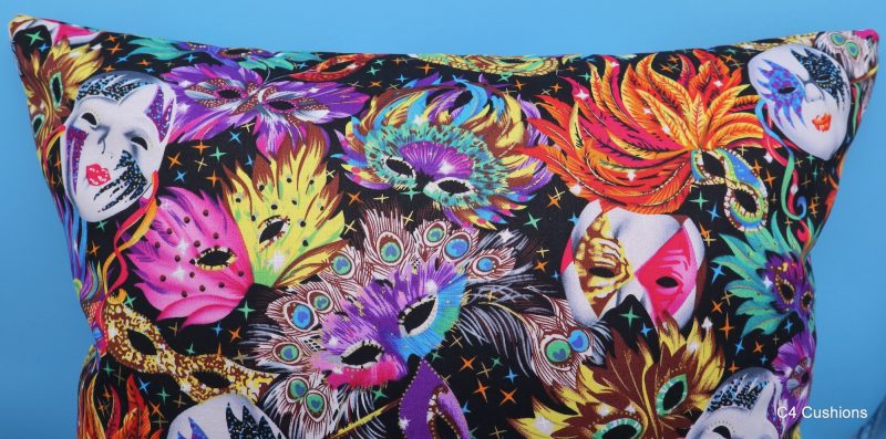 Detail of colourful cushion cover with vibrant carnival masks and feather design on a black background