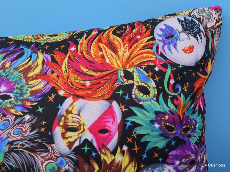 Detail of colourful cushion cover with vibrant carnival masks and feather design on a black background