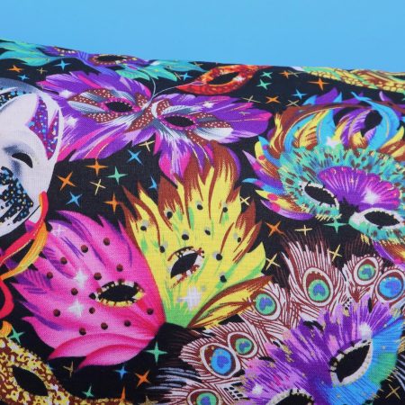 Detail of colourful cushion cover with vibrant carnival masks and feather design on a black background