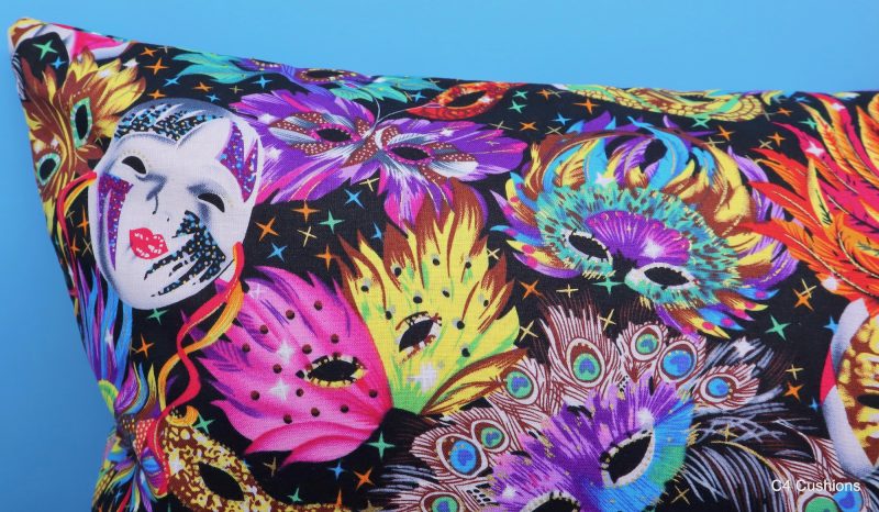 Detail of colourful cushion cover with vibrant carnival masks and feather design on a black background