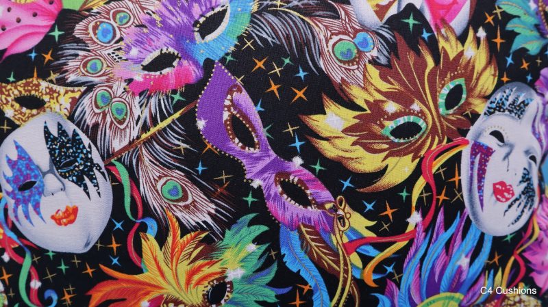 Detail of colourful cushion cover with vibrant carnival masks and feather design on a black background