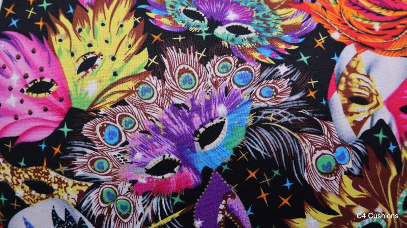 Detail of colourful cushion cover with vibrant carnival masks and feather design on a black background