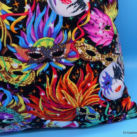 Detail of colourful cushion cover with vibrant carnival masks and feather design on a black background