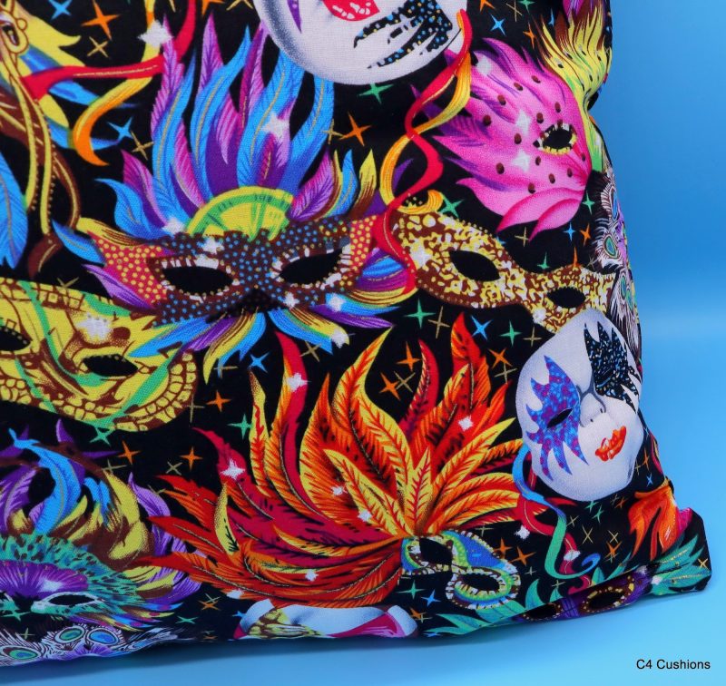 Detail of colourful cushion cover with vibrant carnival masks and feather design on a black background
