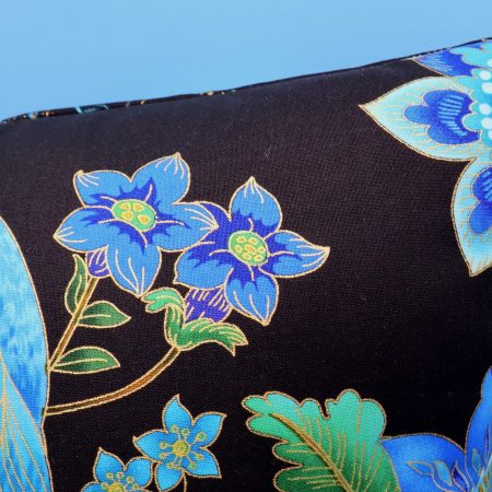 Detail of blue peacock floral cushion cover with vibrant bird design on the front and feather pattern on the reverse