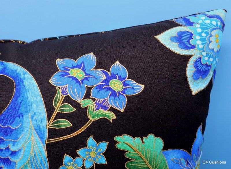 Detail of blue peacock floral cushion cover with vibrant bird design on the front and feather pattern on the reverse