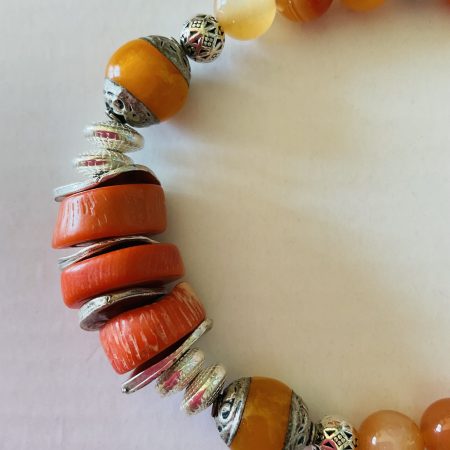 Stretch charm bracelet featuring deep sea coral, carnelian and Tibetan silver