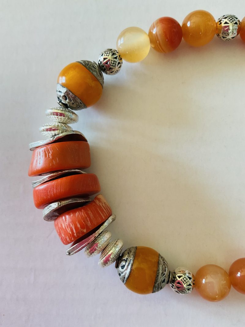 Stretch charm bracelet featuring deep sea coral, carnelian and Tibetan silver