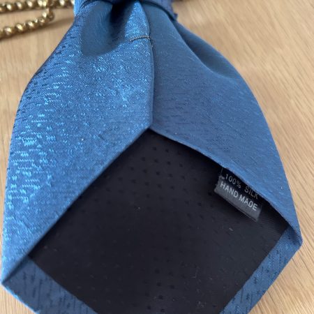 Handmade, elegant blue necktie accessory adorned by a beautiful golden flower brooch.